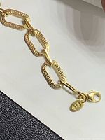 Close-up of bracelet lobster clasp, hallmark tag, and embossed link detail