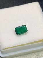 Emerald cut gemstone on white foam showing top facet table and chip