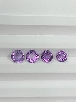 Four round faceted amethysts arranged in a row