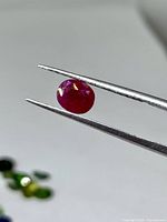 Ruby held in tweezers, showing size and color