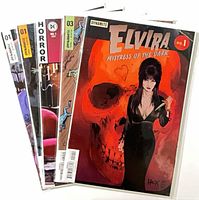 Stack of five bagged comics showing various cover edges.