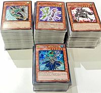 Four tall stacks of sleeved Yu-Gi-Oh! cards