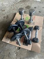 All dumbbells arranged on cardboard showing 2 chrome, 2 hex, 2 adjustable with plates