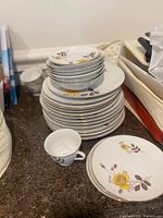 Stacked plates, bowls, cup displaying yellow rose floral china pattern