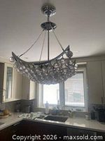 Chandelier unlit, showing chrome frame, crystal spheres, chains and canopy