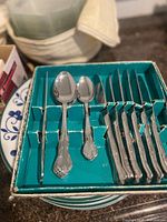 Cutlery set in teal box showing two tablespoons, two cocktail forks and five dinner knives with ornate handles
