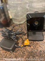 Camera on stand with attached cable and separate power adapter visible