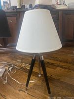 Full view of tripod lamp with shade, cord visible