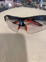 Front view of glasses showing frame, lens, red temples, nosepiece