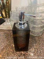 Front view of dark translucent rectangular soap dispenser with chrome pump head
