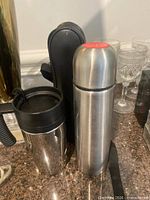 Thermos, carrier bag and travel mug grouped together