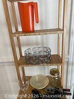 Shelf with orange pitcher, wire bowl, glass tumbler, plate, mason jar, utensils