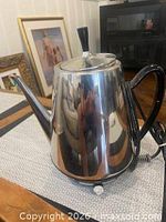 Overall view of stainless steel Sunbeam percolator showing body, spout, handle, lid knob and cord connection