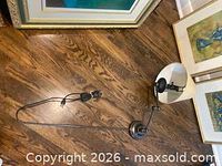 Overall view of metal swing-arm wall lamp with white shade and cord