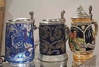 Three steins side by side showing overall design, materials and lids