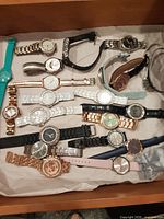 Drawer showing multiple fashion wristwatches with various straps and finishes