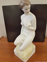 Full front view of kneeling nude woman porcelain figurine