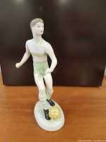 Front view of figurine showing pose, uniform, ball and base