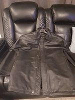 Front view of black leather jacket draped over sofa