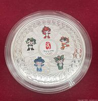 obverse of medallion showing coloured Fuwa mascots and logo in capsule