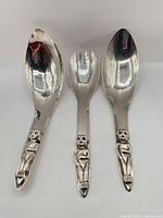 Front view of three silver-plated utensils showing shapes and handles