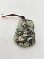 front view of carved jade rabbit pendant with bead and cord
