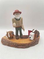 Full view of wood carving showing man, two dogs, natural wood base