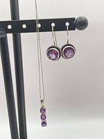 Full view of earrings and pendant on display stand