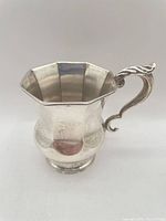 Octagonal small sterling cup with ornate scroll handle