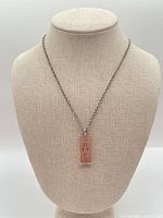 Full view of necklace on display bust showing chain and pendant