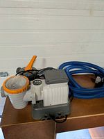 Overall view of Bestway pool pump, blue hose, power cord