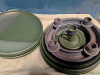 Stack of seven green plates beside stacked dish and candle holders