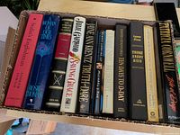 Box of 11 hardcover books showing all spines