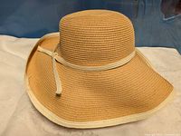 Front view of tan paper straw hat with off-white trim