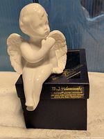 White porcelain seated angel figurine on navy Reutter Porzellan box, front view with gold label visible