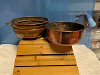 Overall view of both copper pots on wooden crate