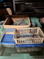 Overview of containers: cardboard box of nails, plastic basket with nails, two lidded bins, all in larger tote