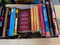 Box of paperbacks showing mix of fiction and non-fiction spines