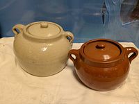 Cream and brown ceramic bean pots with lids side by side