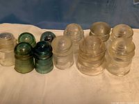 Row of clear and colored glass insulators on cloth backdrop