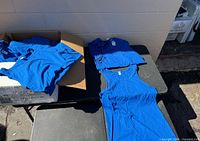 Box and stacks of royal blue tank tops on table