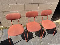 Three orange fabric dining chairs front view showing upholstery and frames