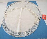 Round white linen mat with lace border, folded center visible