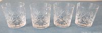 Four cut crystal whiskey glasses aligned side by side