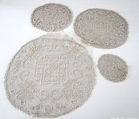 All four round crocheted doilies laid flat showing size differences