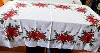 Full view of white poinsettia Christmas tablecloth spread on table