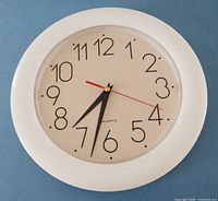 front view of round white quartz wall clock showing face and hands