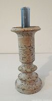 Front view of marble candle holder with blue taper candle inserted