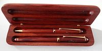 Open wooden case showing fountain and ballpoint pens