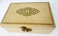 Closed tan jewellery box showing scroll motif and front lock